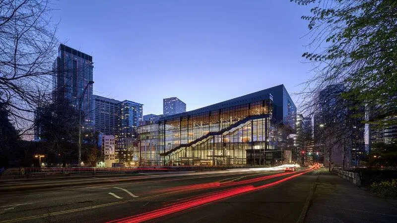 The Seattle Convention Center Summit Building at dusk, its glazed street frontage lit from within.