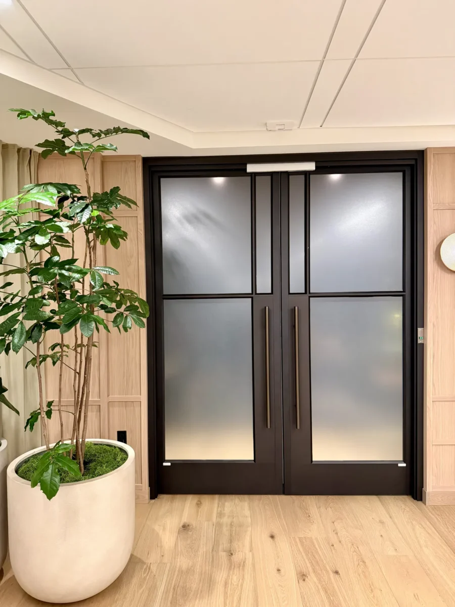 Interior glazing at 1201 NW 3rd: black-framed glass doors, partitions and mirrors on the building amenity floor.