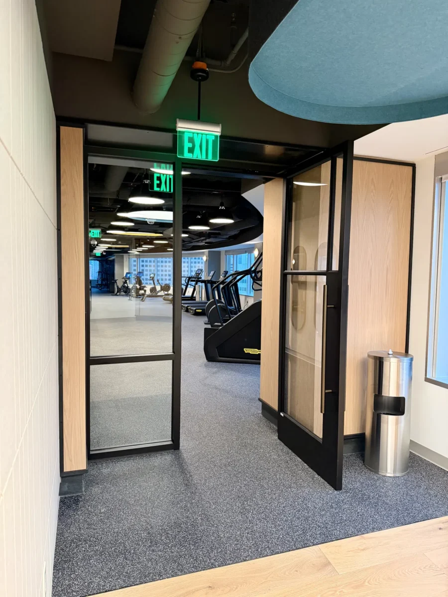 Interior glazing at 1201 NW 3rd: black-framed glass doors, partitions and mirrors on the building amenity floor.