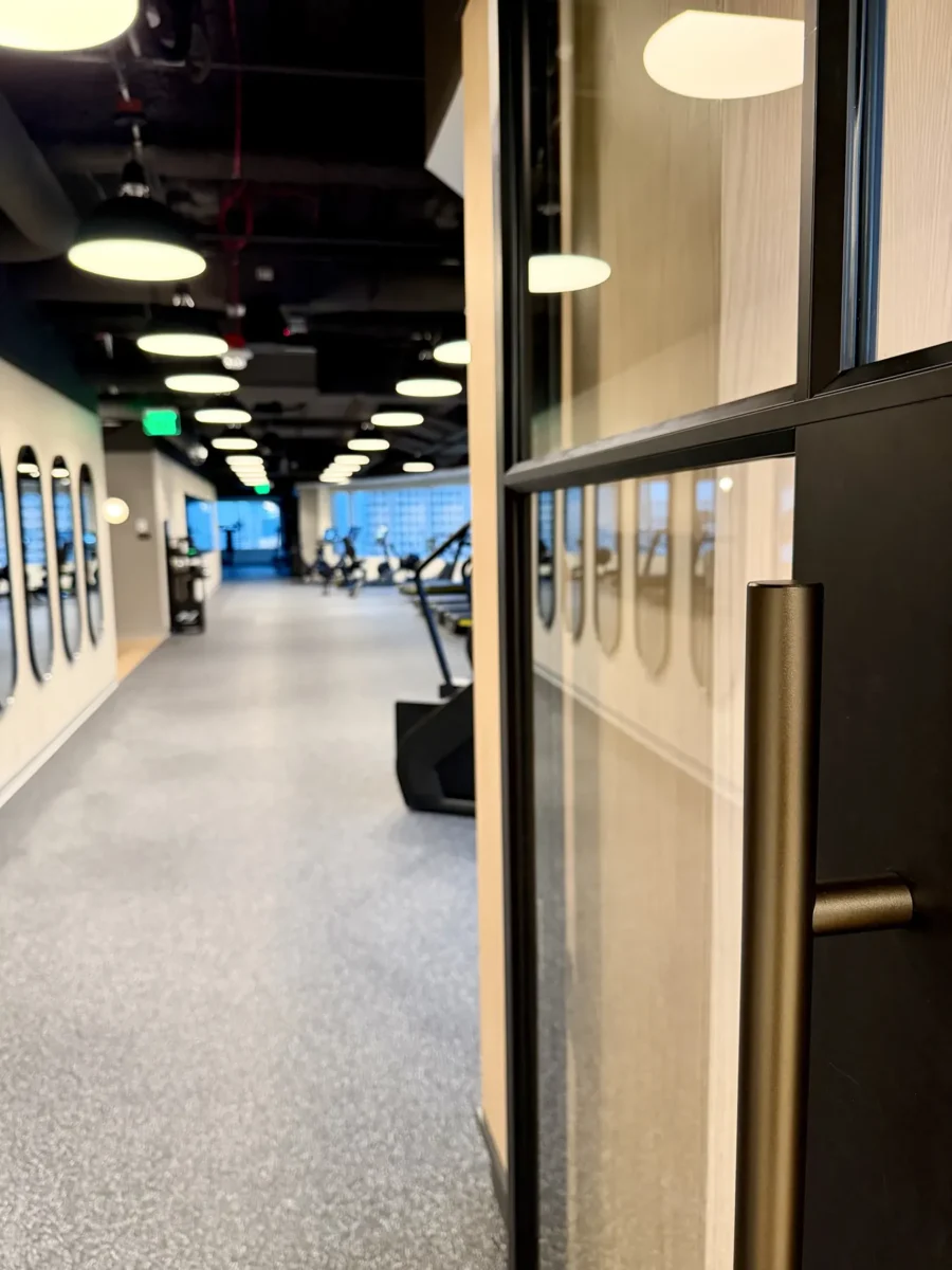 Interior glazing at 1201 NW 3rd: black-framed glass doors, partitions and mirrors on the building amenity floor.