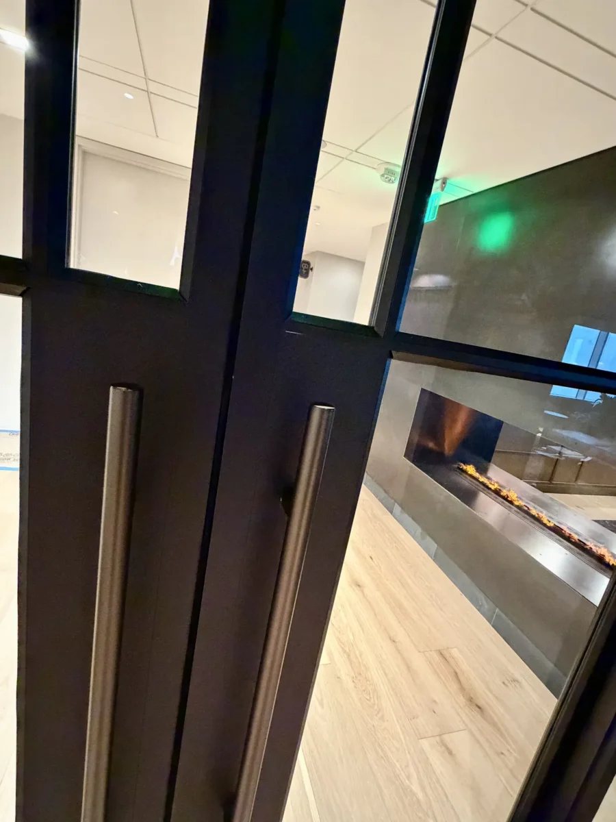 Interior glazing at 1201 NW 3rd: black-framed glass doors, partitions and mirrors on the building amenity floor.
