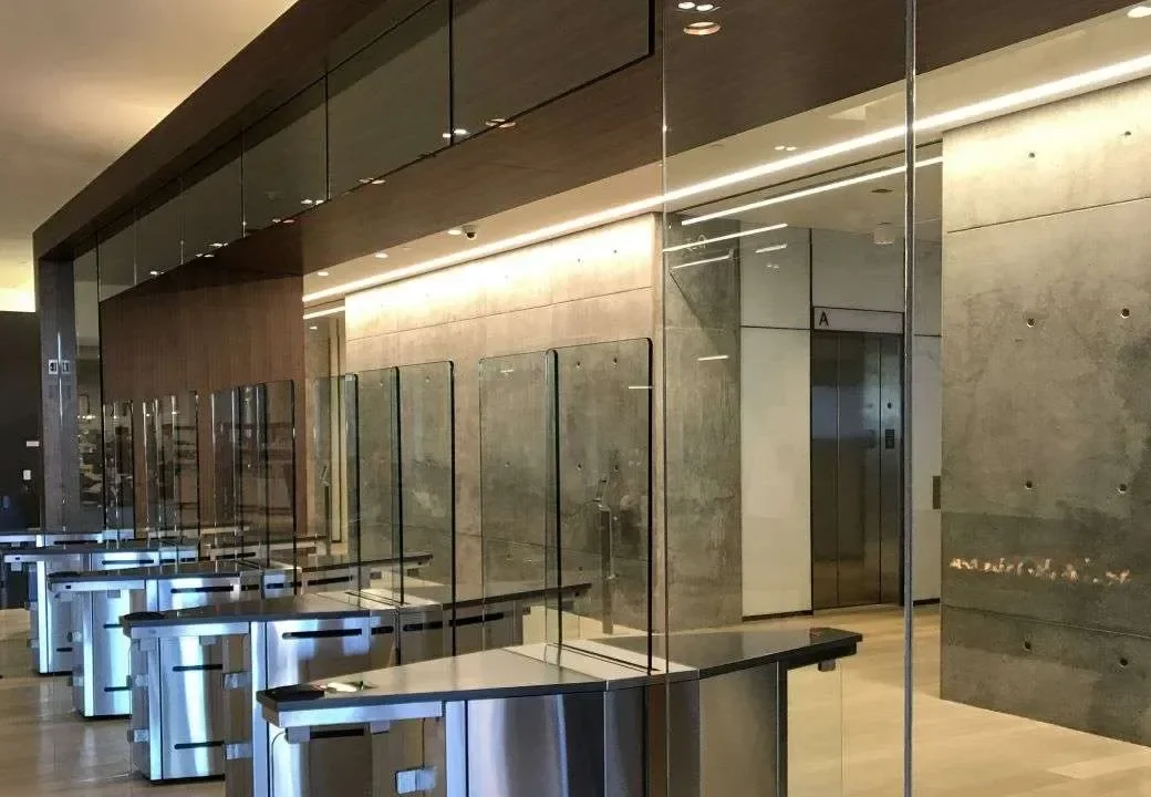 A finished lobby with frameless glass partitions and polished metal fixtures.