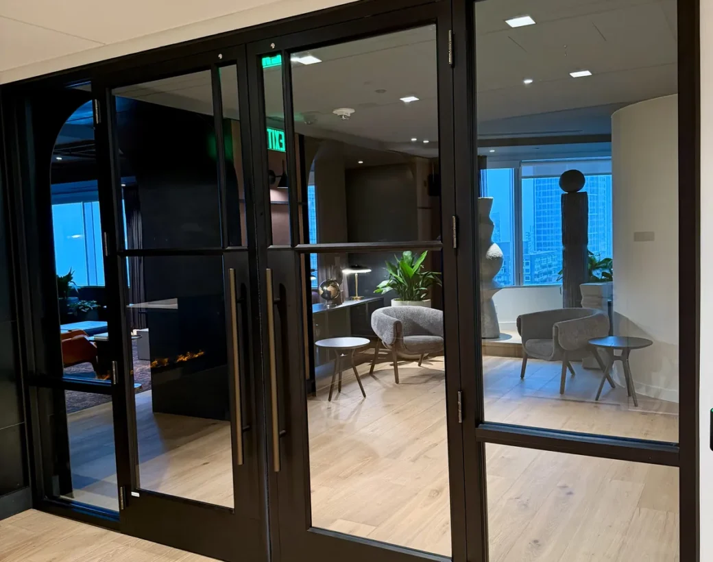 Black-framed glass entrance doors into an office lounge