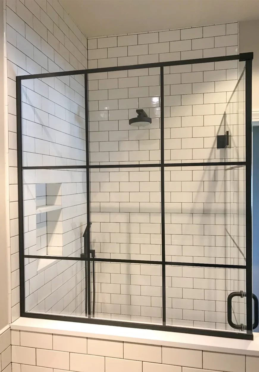 Black steel grid glass shower enclosure with white subway tile