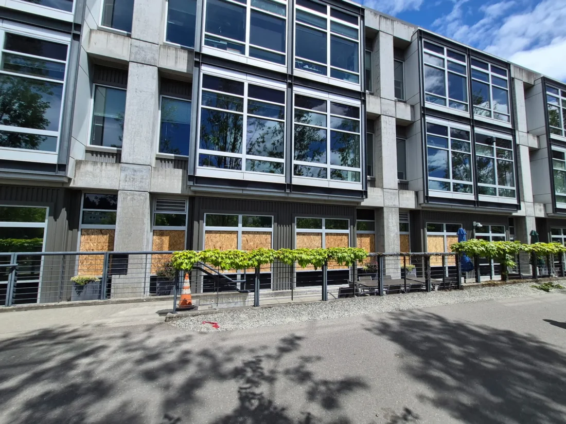 Ground-floor windows boarded up to secure the building after glass damage