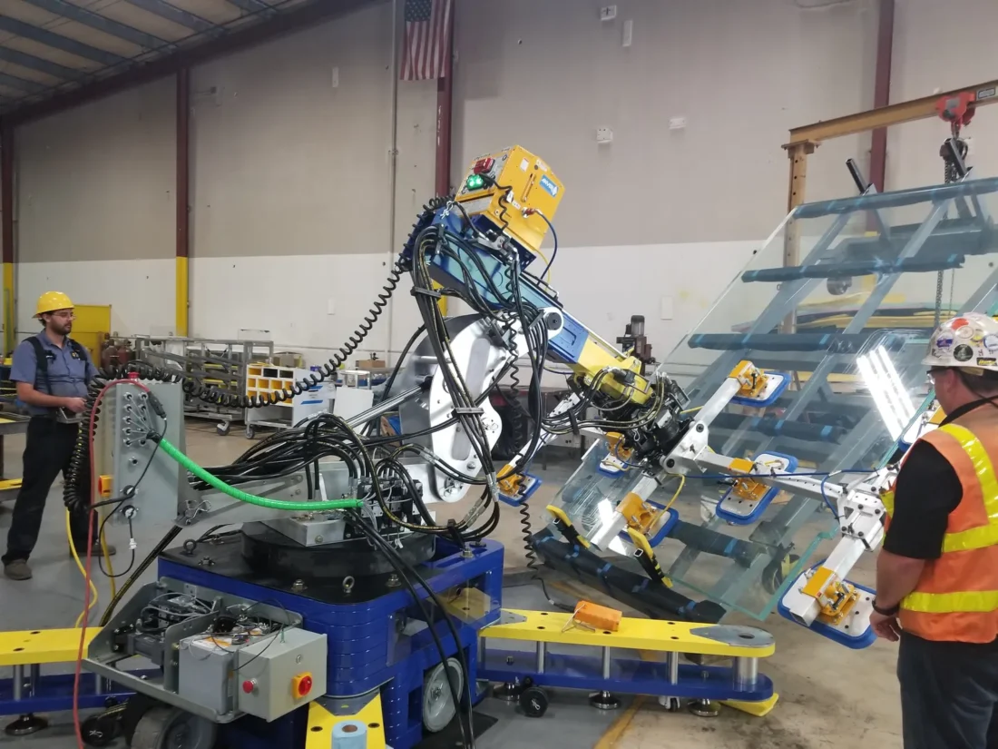 Glaziers operating a robotic handler with a glass panel in the shop