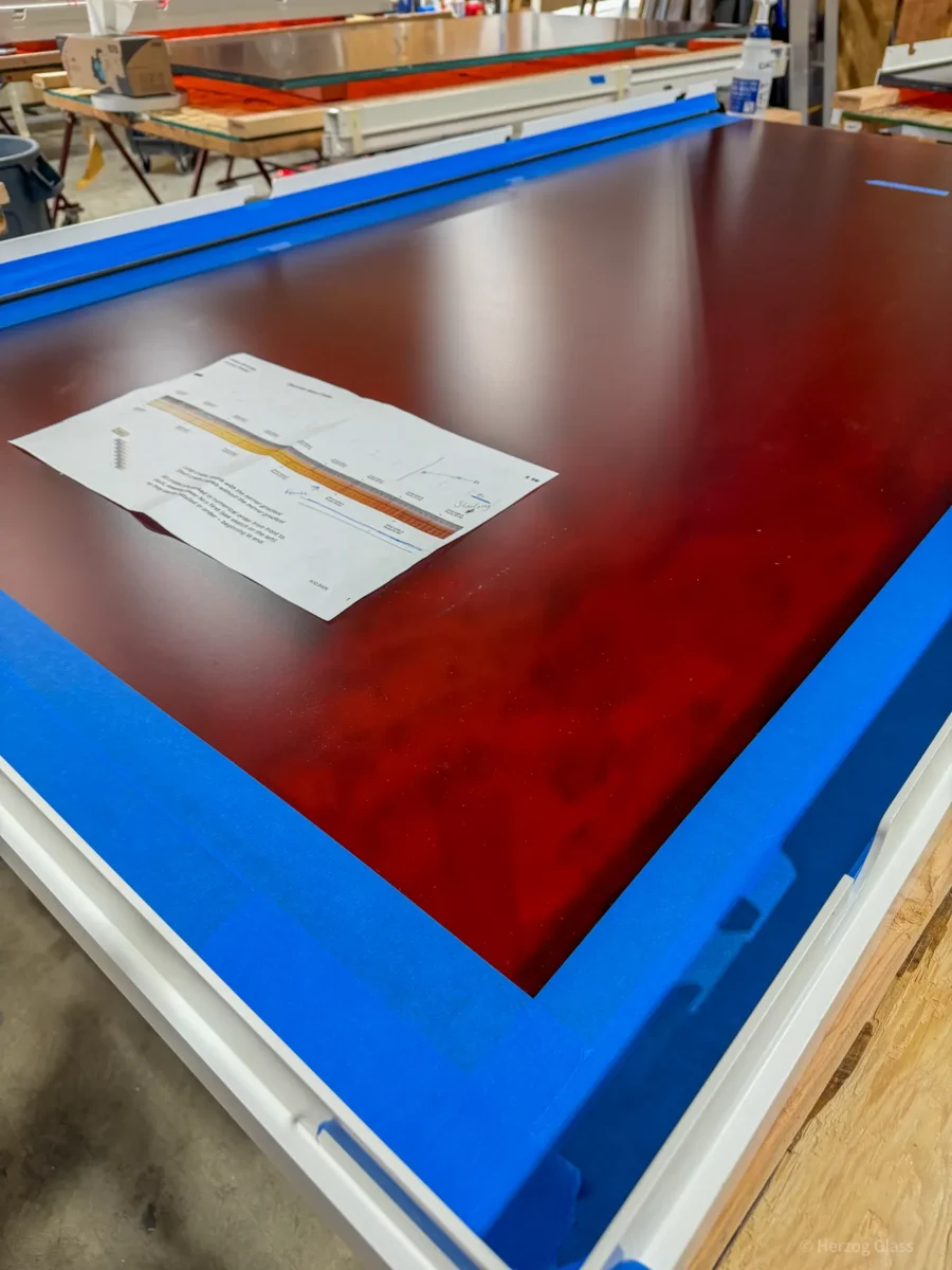 Aluminum and glass canopy assemblies and their shop drawings on the fabrication floor.