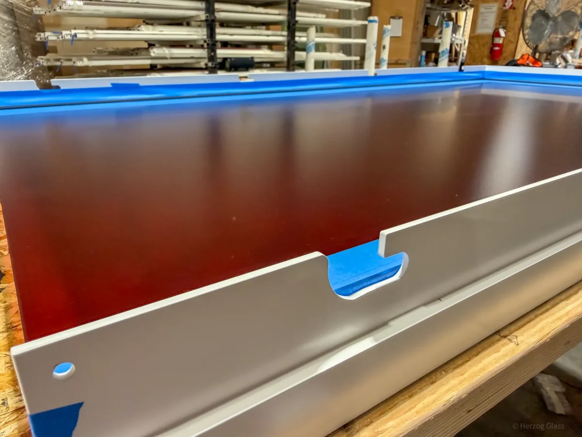 Aluminum and glass canopy assemblies and their shop drawings on the fabrication floor.