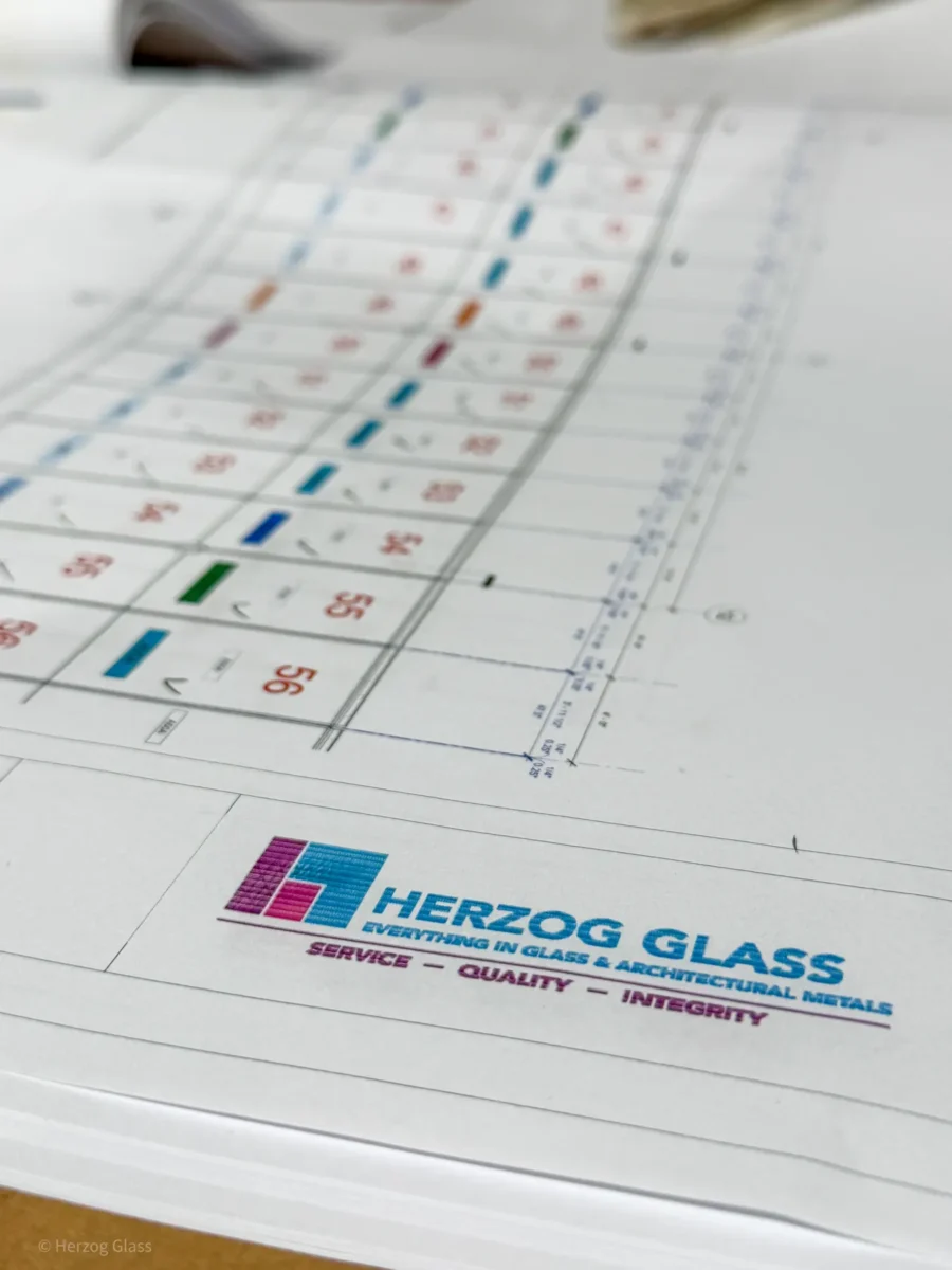 Aluminum and glass canopy assemblies and their shop drawings on the fabrication floor.