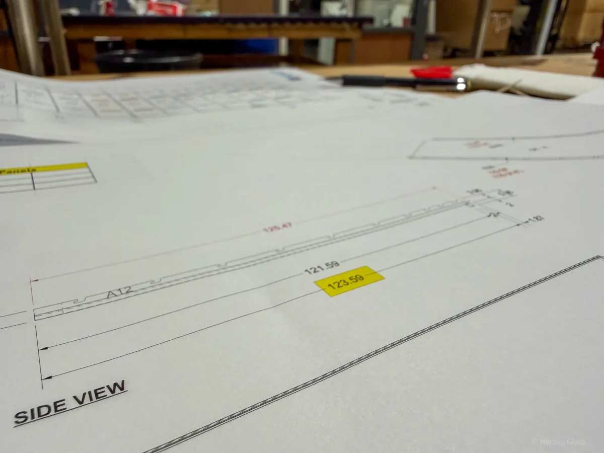 Aluminum and glass canopy assemblies and their shop drawings on the fabrication floor.