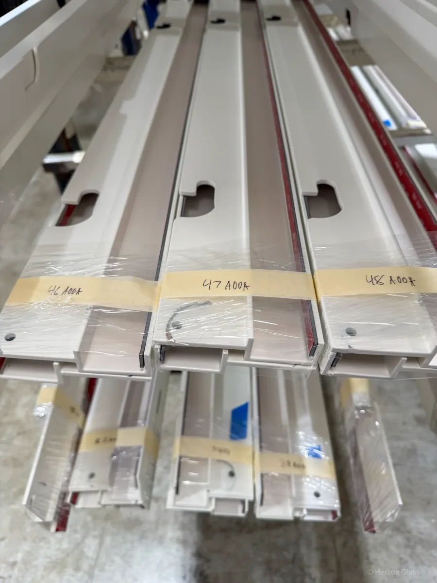 Aluminum and glass canopy assemblies and their shop drawings on the fabrication floor.