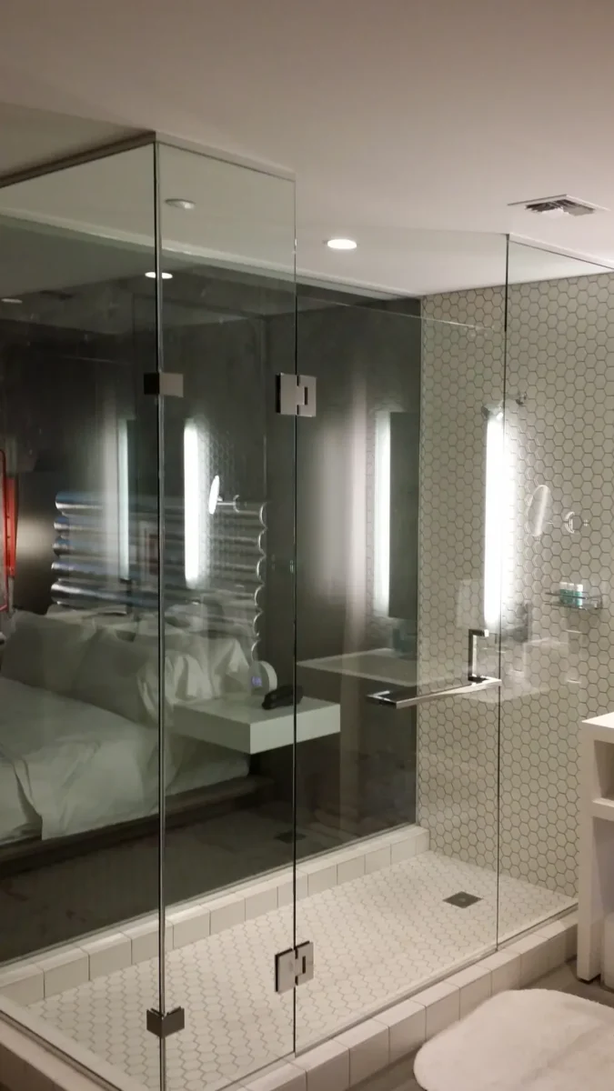 A frameless glass shower enclosure in a tiled bathroom.
