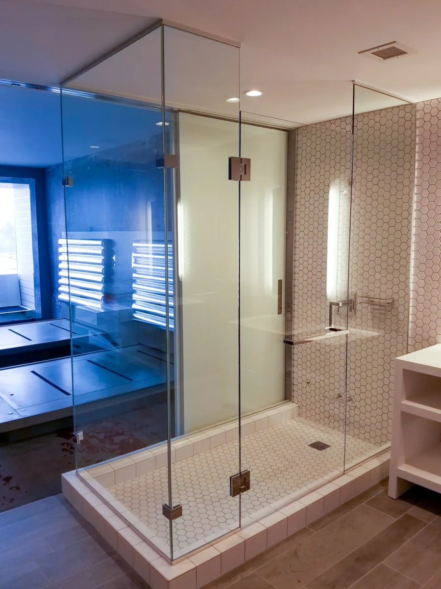 A frameless glass shower enclosure in a tiled bathroom.