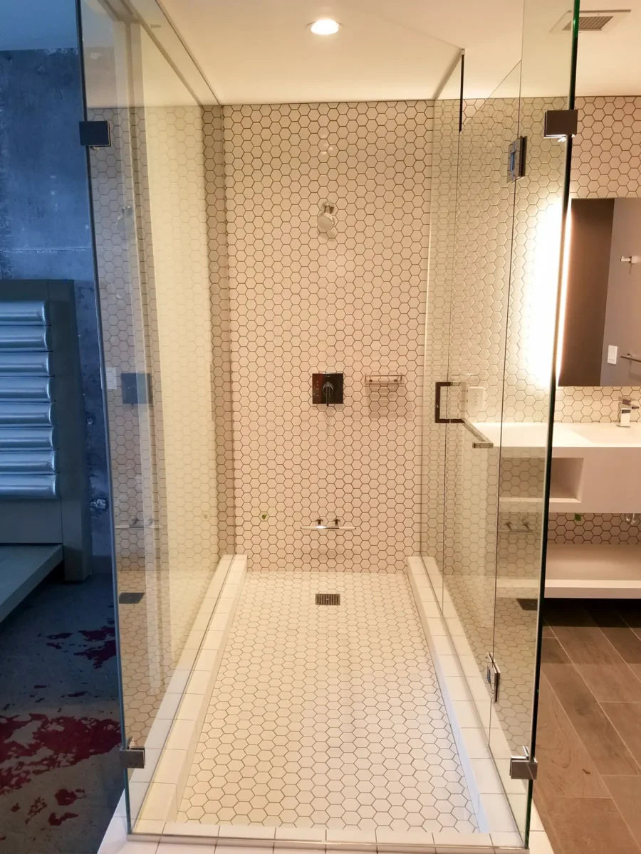 A frameless glass shower enclosure in a tiled bathroom.