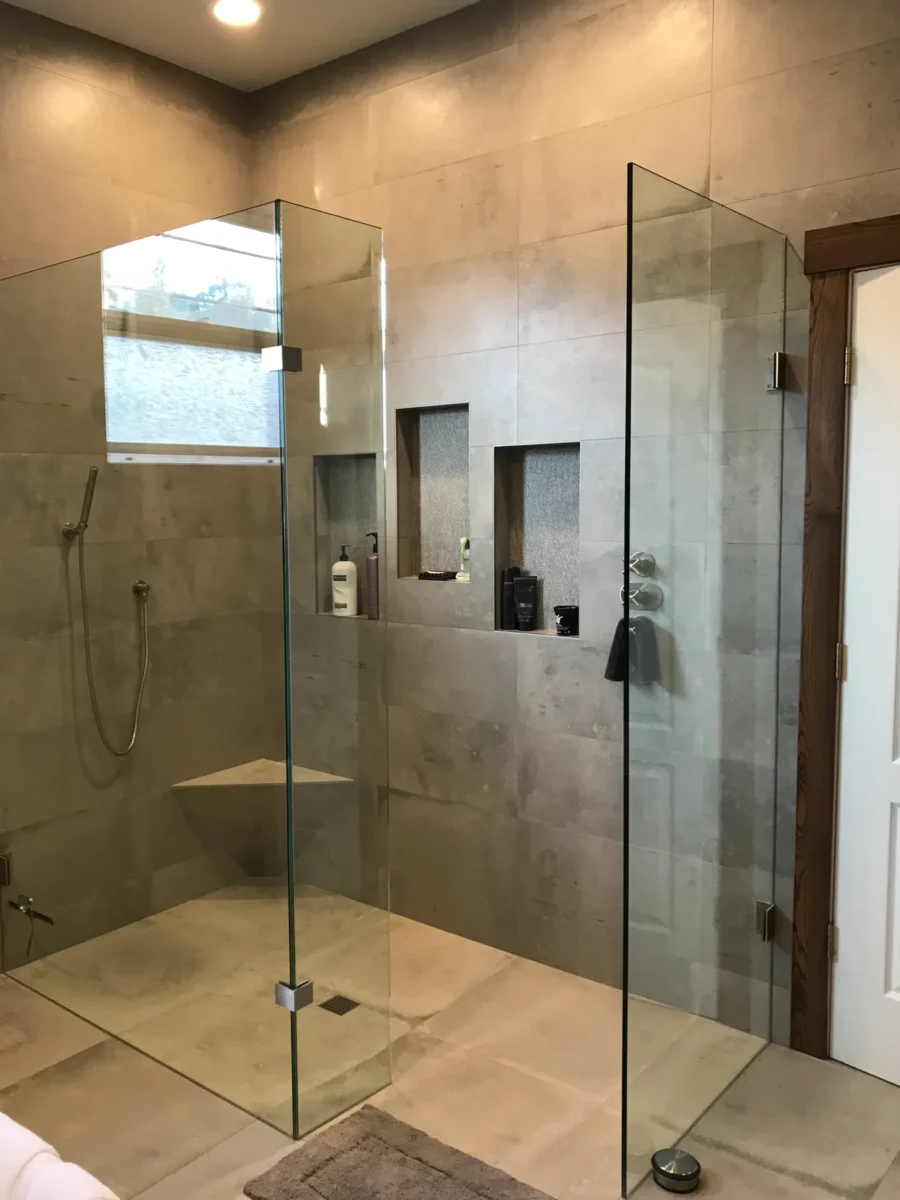 A frameless glass shower enclosure in a tiled bathroom.