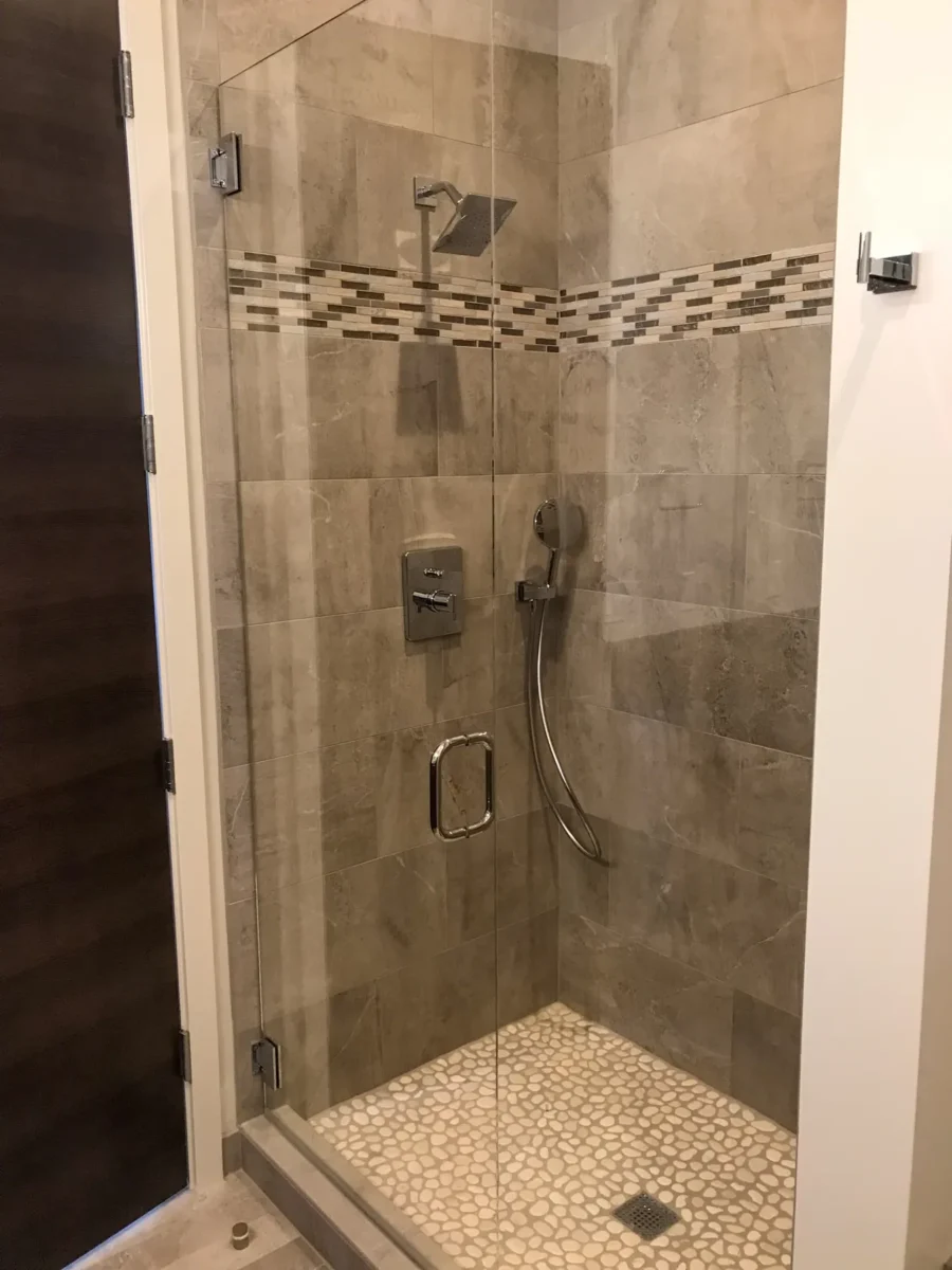 A frameless glass shower enclosure in a tiled bathroom.