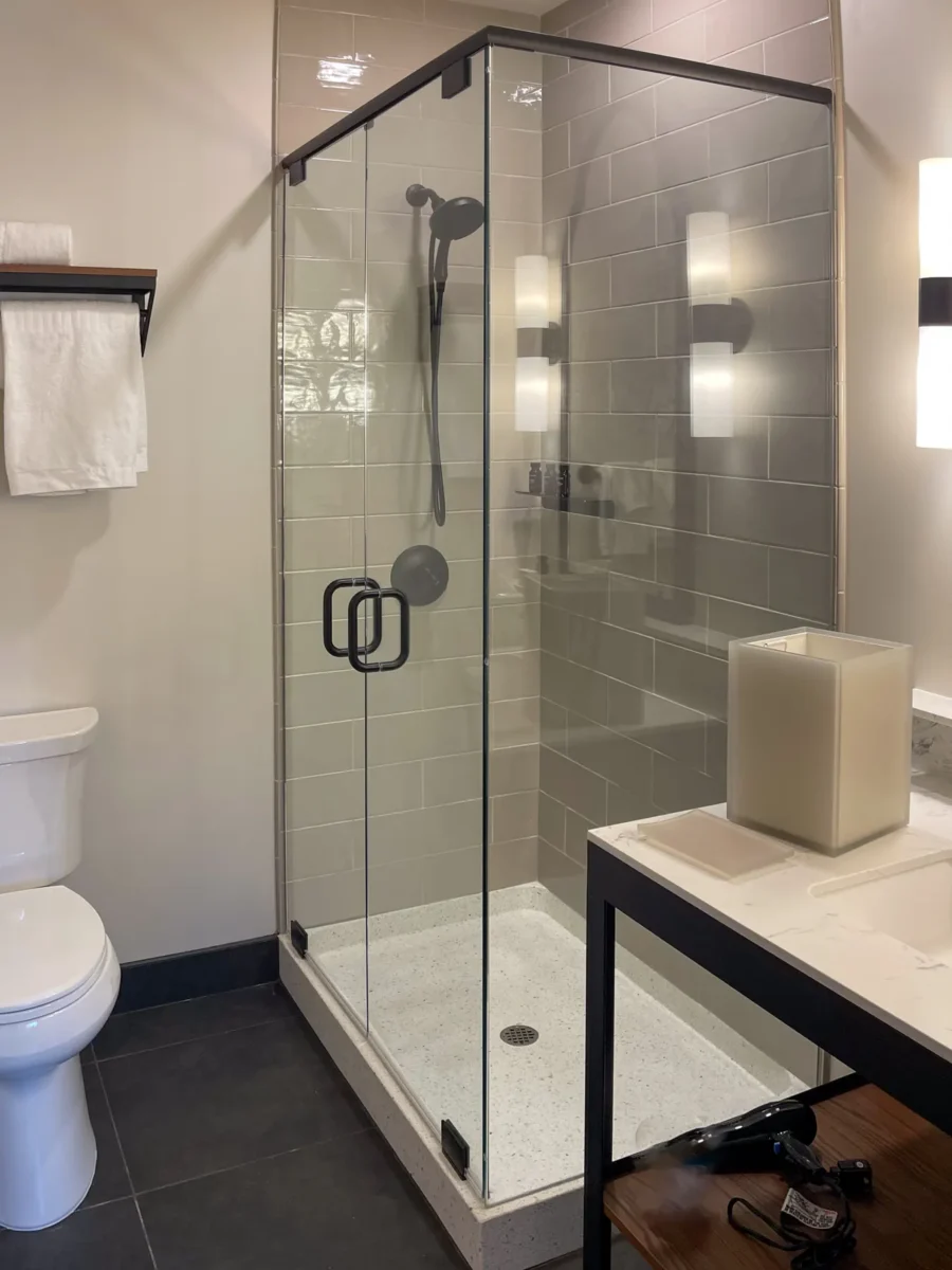 A frameless glass shower enclosure in a tiled bathroom.