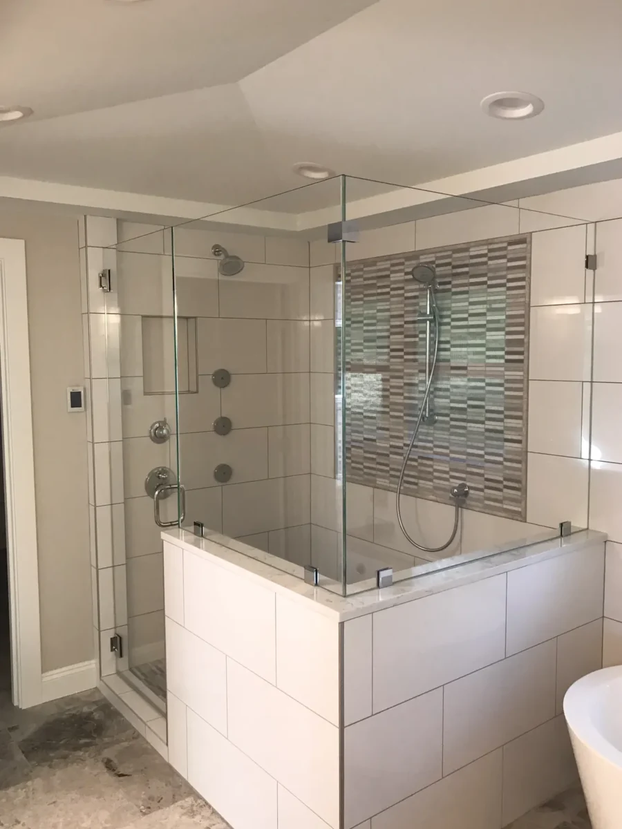 A frameless glass shower enclosure in a tiled bathroom.