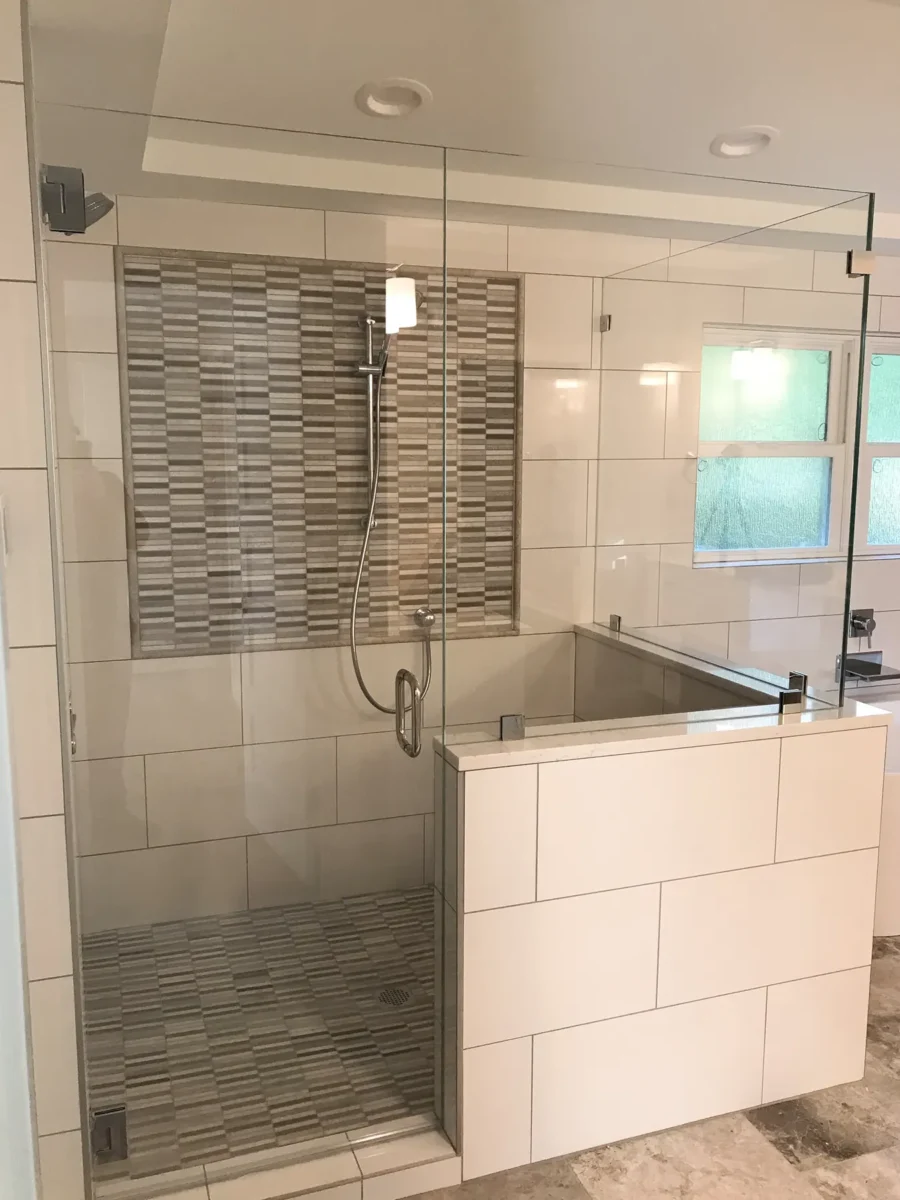A frameless glass shower enclosure in a tiled bathroom.