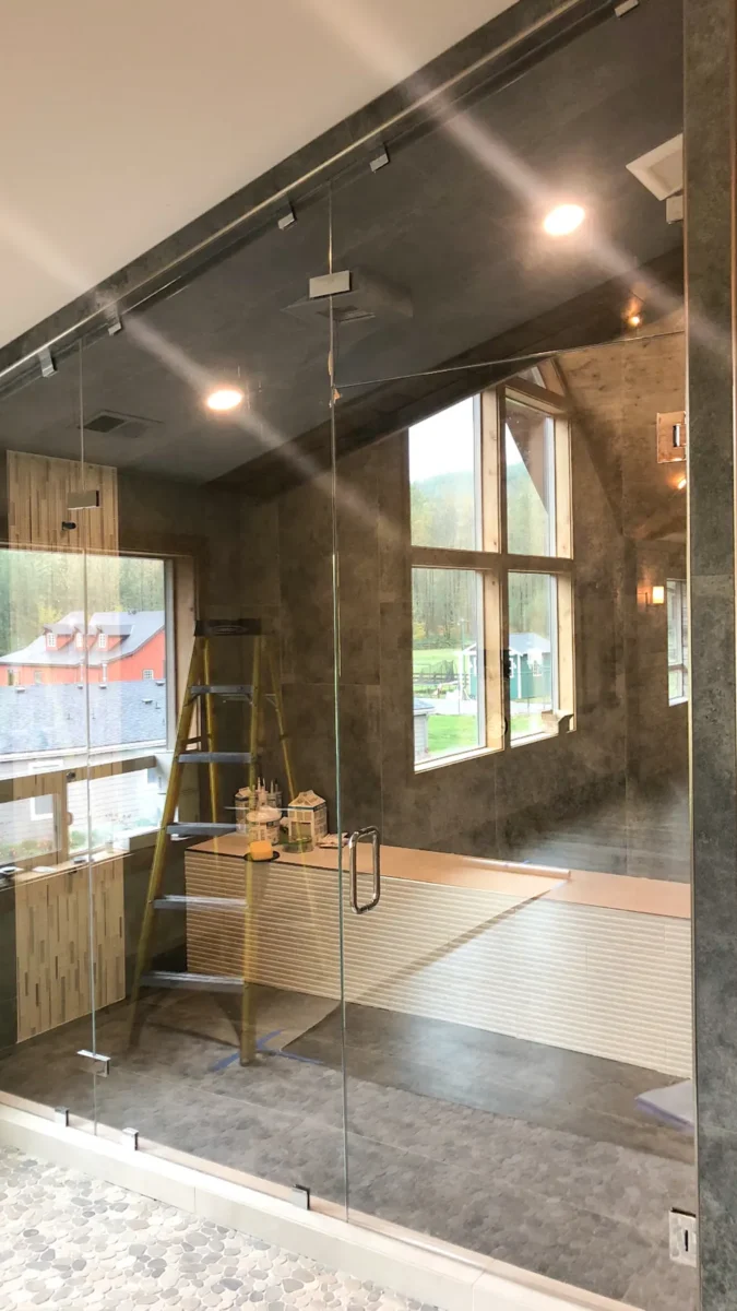 A frameless glass shower enclosure in a tiled bathroom.