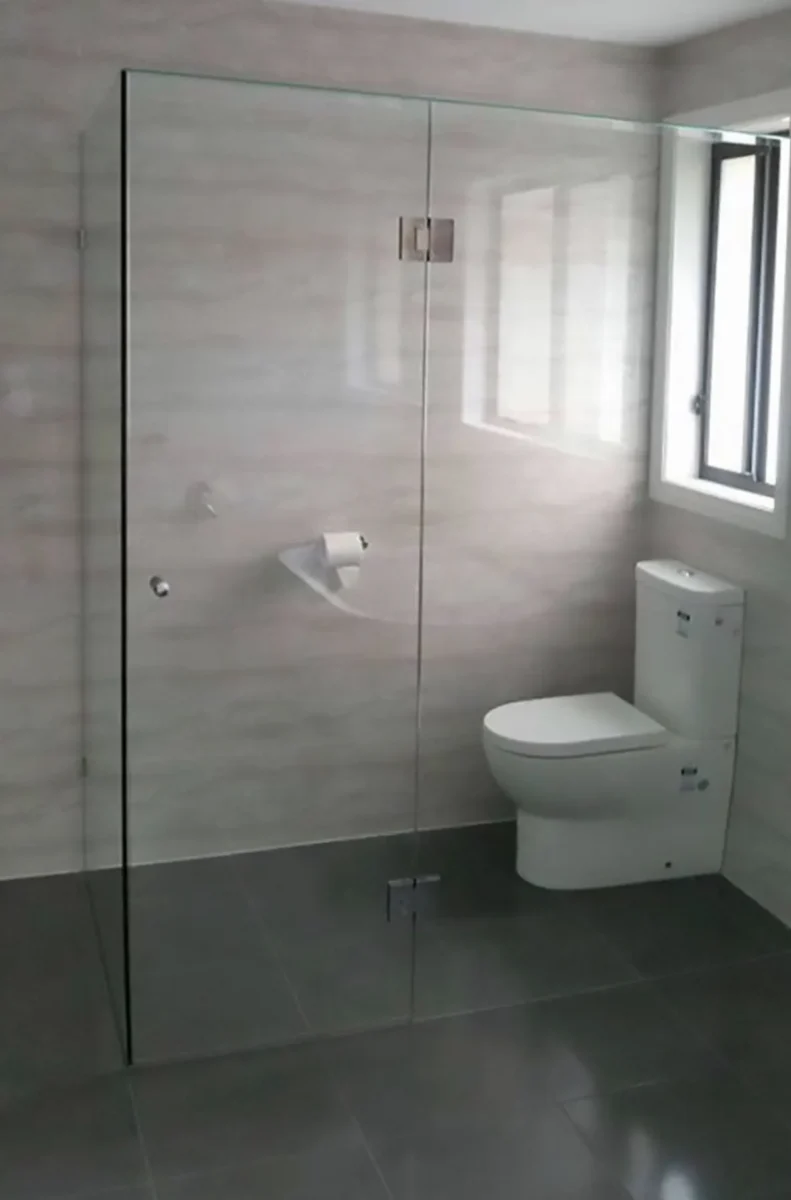A frameless glass shower enclosure in a tiled bathroom.