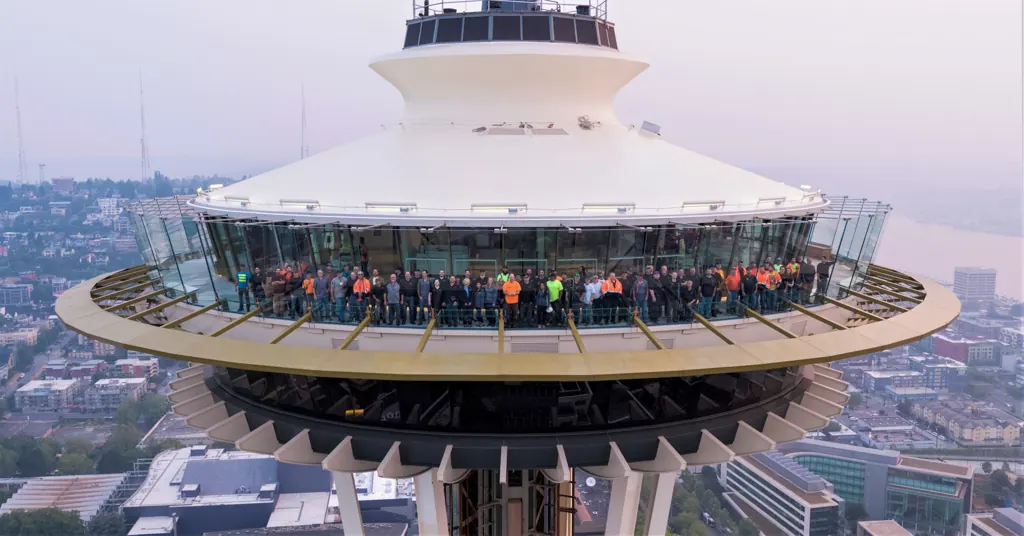 The Herzog Glass crew lined up along the Space Needle observation deck, behind the glass they installed.