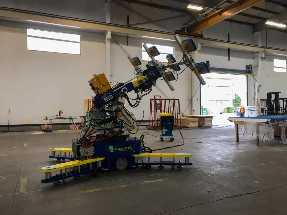 A glass handling robot lifting an oversized panel in the Herzog Glass fabrication shop
