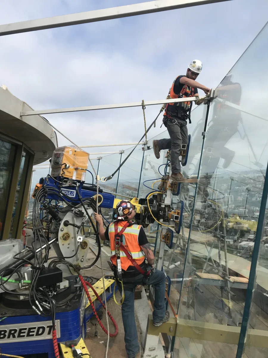 A glazier on the lift fitting one of the outward-leaning glass panels on the Space Needle