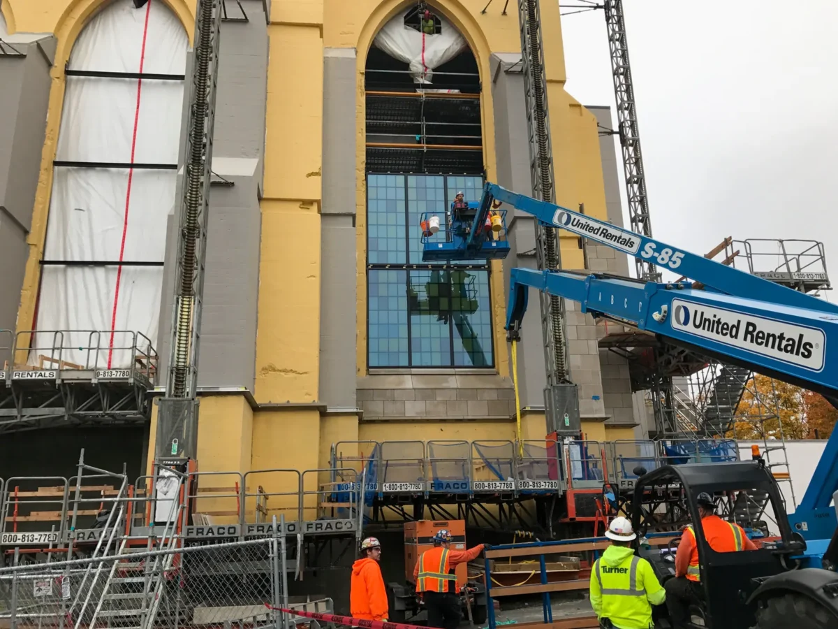 Colored glass panels in the arched windows of St Mark’s Cathedral, and the same panels on the shop floor before installation.