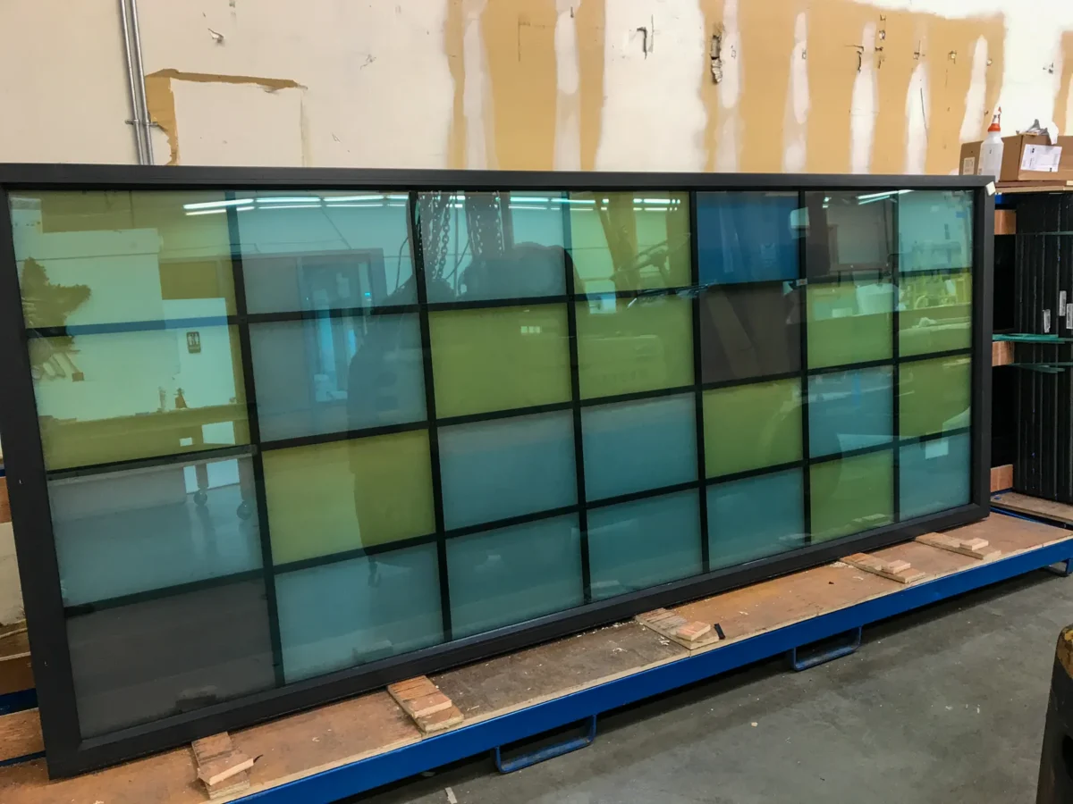 Colored glass panels in the arched windows of St Mark’s Cathedral, and the same panels on the shop floor before installation.