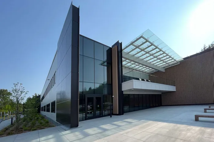 A commercial building with a dark glazed facade and a glass canopy entry.