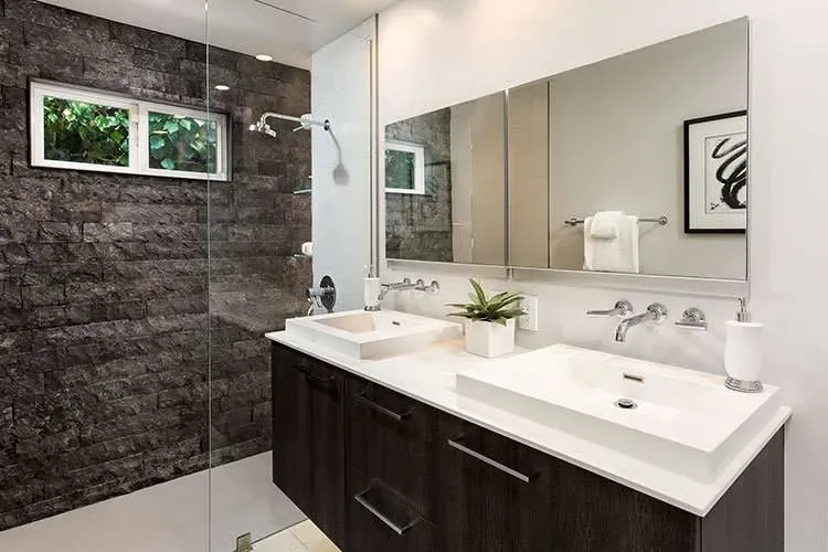 A residential bathroom with a frameless glass shower enclosure and mirrors.