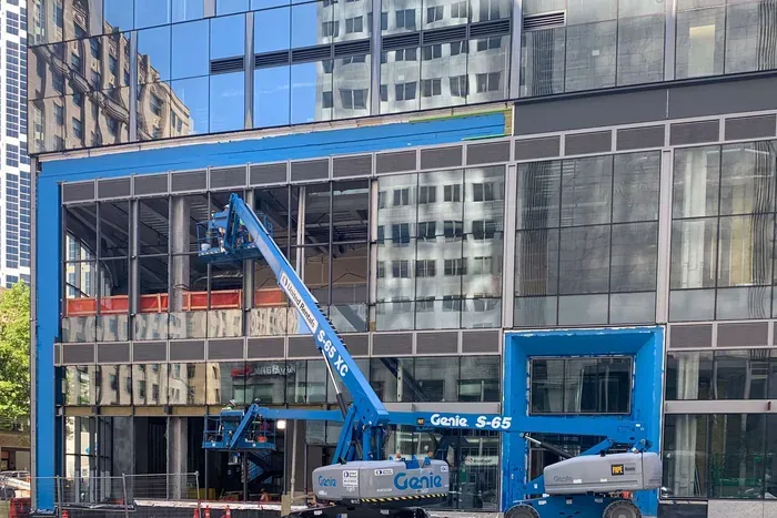 A boom lift raised against a storefront during a glass replacement.